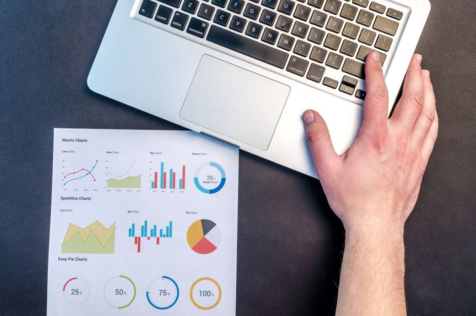 Computadora y reportes gráficos para revisar el rendimiento comercial
