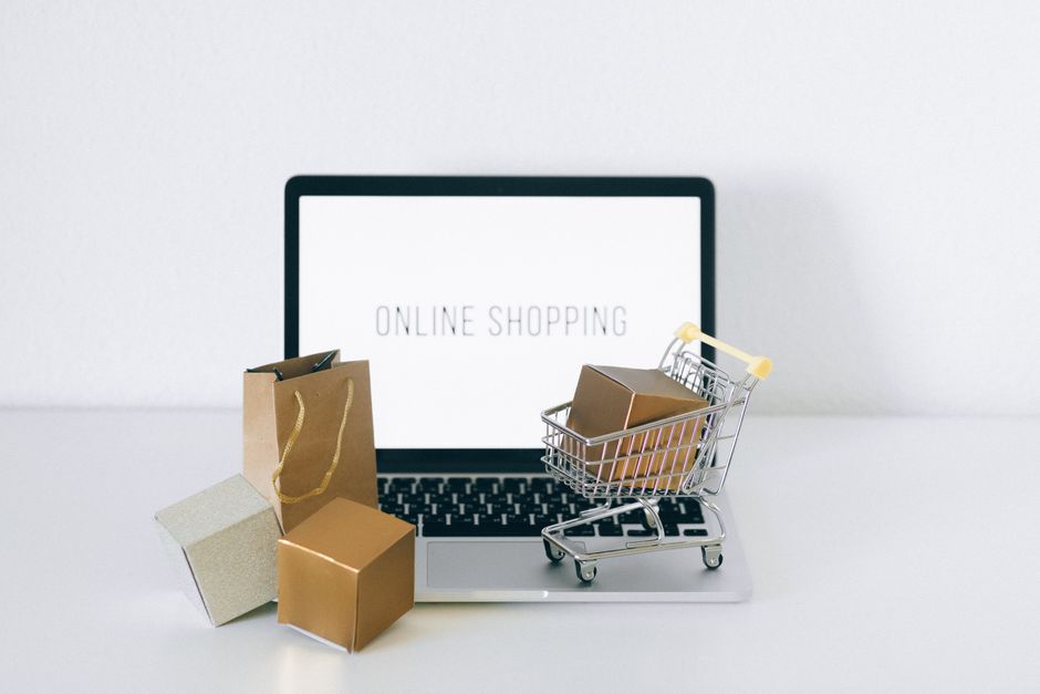 Computadora, bolsas y carrito que representan una tienda en línea