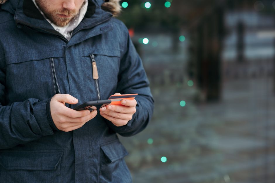 Persona usando su teléfono y una tarjeta para completar un pago